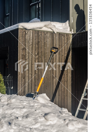 Snow shovel resting in a snowdrift after winter work. Snow shovel resting in a snowdrift after winter work. 135836454