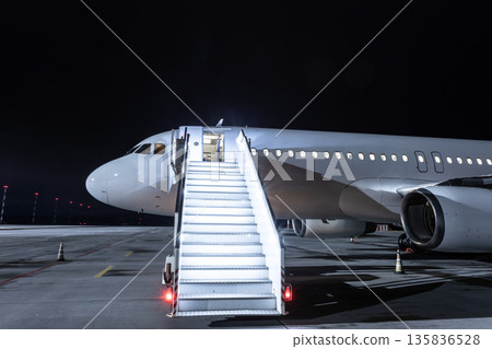 Modern passenger airliner with staircase at the night airport Modern passenger airliner with staircase at the night airport 135836528