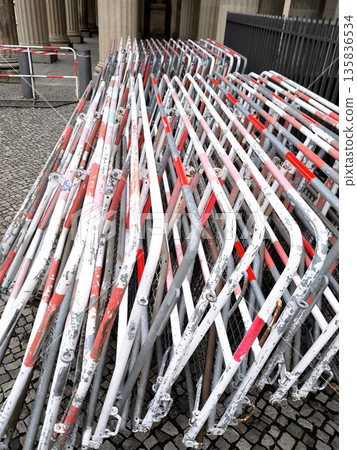A stack of folding metal barriers with red and white stripes on a city pavement A stack of folding metal barriers with red and white stripes on a city pavement 135836534