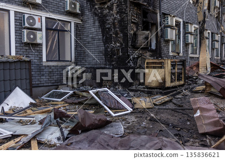 Charred wall and damaged air conditioners mark the aftermath of a severe fire, with twisted debris and burnt materials scattered across the ground in a devastated urban setting. Charred wall and damaged air conditioners mark the aftermath of a severe fire, with twisted debris and burnt materials scattered across the ground in a devastated urban setting. 135836621