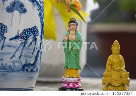 Statue of a woman is sitting on a pedestal next to a vase 135837324