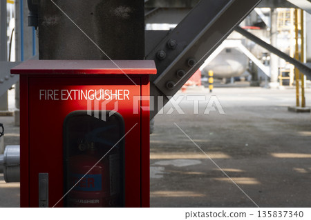 Red fire extinguisher is sitting on the ground Red fire extinguisher is sitting on the ground 135837340