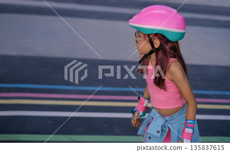 Young girl roller skating on an outdoor track, wearing a helmet and protective gear, enjoying active urban recreation, movement and freedom with copy space Young girl roller skating on an outdoor track, wearing a helmet and protective gear, enjoying active urban recreation, movement and freedom with copy space 135837615