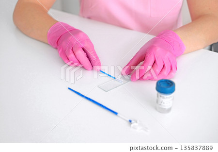 Laboratory technician in pink gloves preparing medical sample on glass slide for diagnostic testing. Healthcare, clinical analysis, research and laboratory procedure concept Laboratory technician in pink gloves preparing medical sample on glass slide for diagnostic testing. Healthcare, clinical analysis, research and laboratory procedure concept 135837889