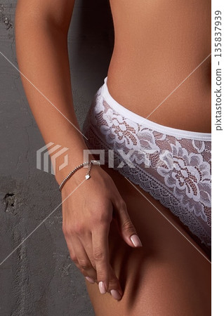 Woman in white lace panties with silver bracelet, close-up on body and hand Woman in white lace panties with silver bracelet, close-up on body and hand 135837939