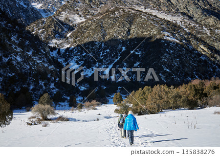 Woman and man trekking through a snowy mountain landscape, adventure sports, winter hiking activity for leisure and active lifestyle. 135838276