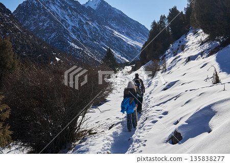 Woman and man trekking through a snowy mountain trail, hiking in winter landscape. Adventure and healthy lifestyle concept. Woman and man trekking through a snowy mountain trail, hiking in winter landscape. Adventure and healthy lifestyle concept. 135838277