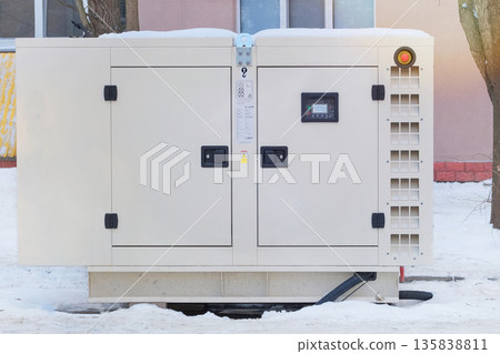 Large diesel generator is running outside in winter. Energy independence and maintenance. Power supply generator placed on street sidewalk. Large diesel generator is running outside in winter. Energy independence and maintenance. Power supply generator placed on street sidewalk. 135838811