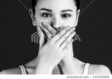Woman silencing self with hands covering mouth 135838896