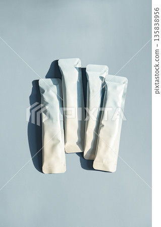 Several white sachet packages with copy space on light blue background. 135838956