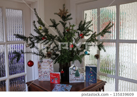 A Christmas tree with many ornaments and a card that says Merry Christmas A Christmas tree with many ornaments and a card that says Merry Christmas 135839609