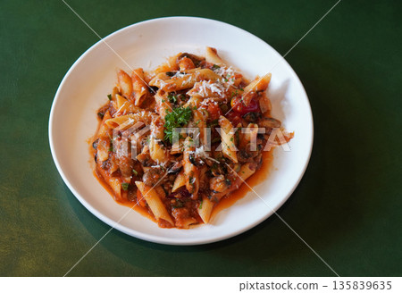 top view hot pasta spaghetti tossed in a rich, chunky tomato-based sauce, mushroom and Cheese and vegetables on white ceramic plate, leather green background, food, health, copy space 135839635