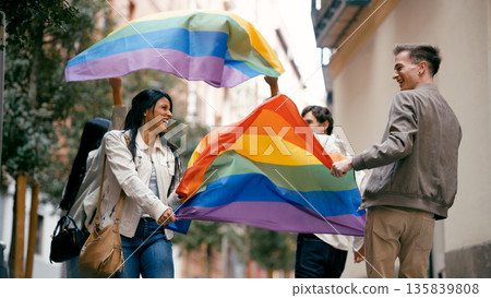 Diverse friends walking carrying rainbow flag Diverse friends walking carrying rainbow flag 135839808