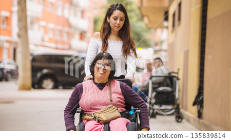 Woman with disability smiling in wheelchair assisted by friend Woman with disability smiling in wheelchair assisted by friend 135839814