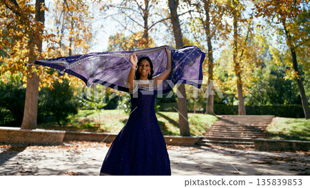 Indian woman smiling playfully, dancing in autumn park Indian woman smiling playfully, dancing in autumn park 135839853