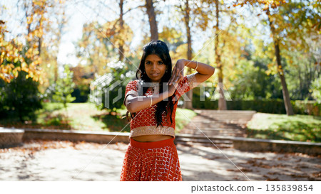 Indian woman dancing traditional bollywood performance in park Indian woman dancing traditional bollywood performance in park 135839854