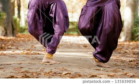 Indian women dancing barefoot in traditional dhoti pants outdoors Indian women dancing barefoot in traditional dhoti pants outdoors 135839856