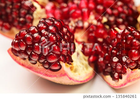 A close up of a red pomegranate fruit with a few seeds visible 135840261