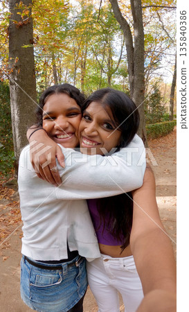 Two indian women hugging outdoor in autumn park 135840386