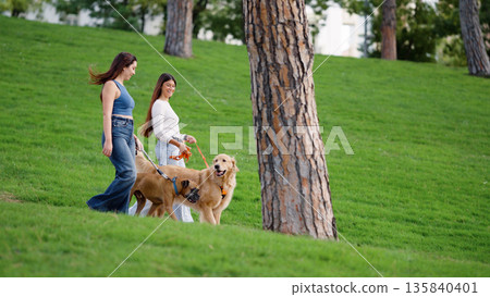 Women walking dogs in park enjoying leisure time Women walking dogs in park enjoying leisure time 135840401