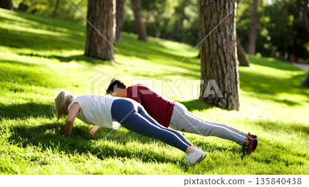 Couple doing push ups together during outdoor workout Couple doing push ups together during outdoor workout 135840438