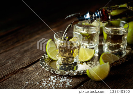 Tequila with salt and lime slices on a silver tray. Tequila with salt and lime slices on a silver tray. 135840500
