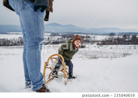 Little boy with father sledding together. Little boy with father sledding together. 135840659