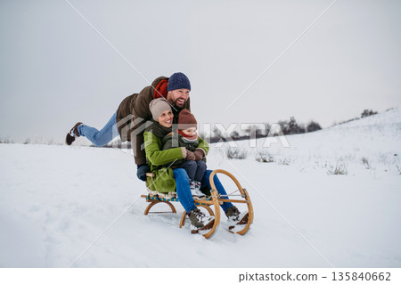 Winter family adventure with parents and little son sledding. 135840662