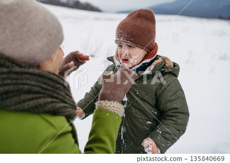 Mom wiping snow from crying child's face after winter play 135840669