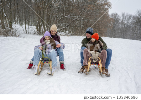 Family enjoying winter sledding together on snowy hill. Family enjoying winter sledding together on snowy hill. 135840686