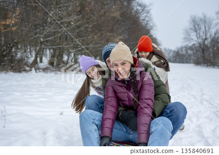 Family enjoying winter sledding together on snowy hill. 135840691