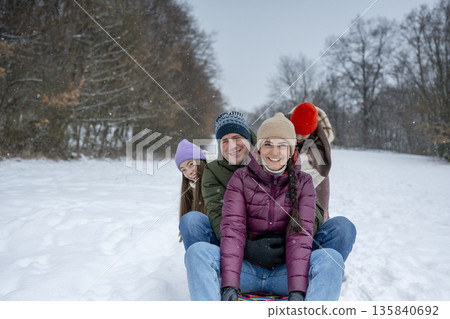 Family enjoying winter sledding together on snowy hill. Family enjoying winter sledding together on snowy hill. 135840692