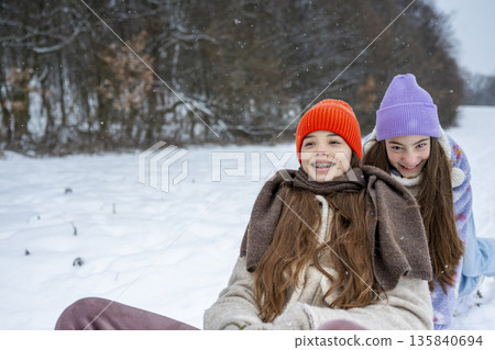 Sisters sledding together and experiencing winter excitement. Sisters sledding together and experiencing winter excitement. 135840694