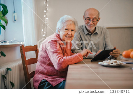 Senior man and woman making reservation online, using tablet. Senior man and woman making reservation online, using tablet. 135840711