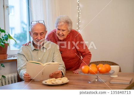 Older couple bonding and talking about book. Older couple bonding and talking about book. 135840713