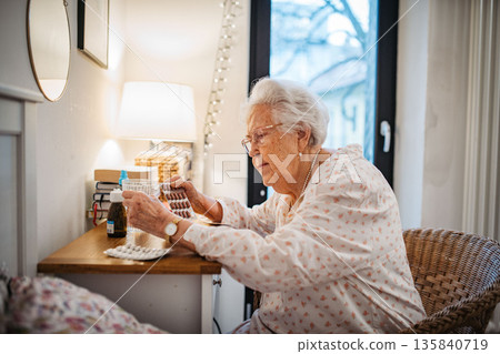Senior woman taking prescribed pills after waking up. 135840719