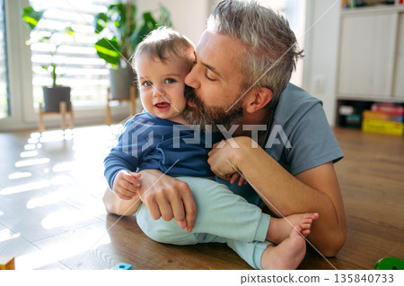 Father playing with little son on floor. 135840733