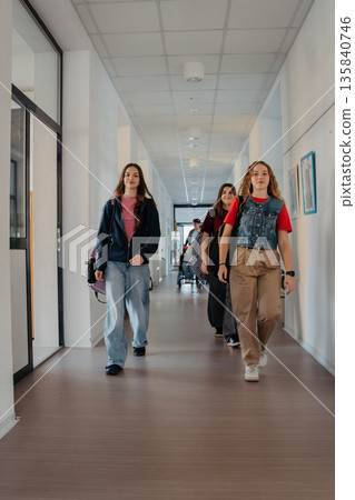 Group of teen girls walking down the hallway in high school. 135840746