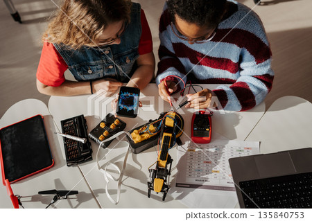 High school students working on robotics project, using online AI app to answer questions. 135840753