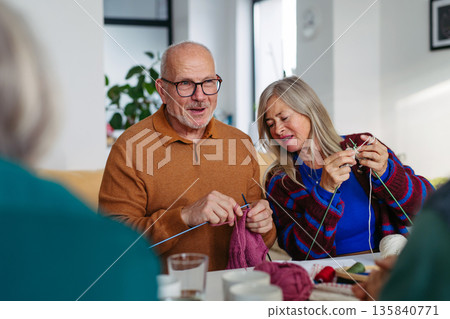 Group of senior people learning knitting together with caregiver tutor in a community center. 135840771