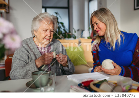 Group of senior people learning knitting together with caregiver tutor in a community center. Group of senior people learning knitting together with caregiver tutor in a community center. 135840772
