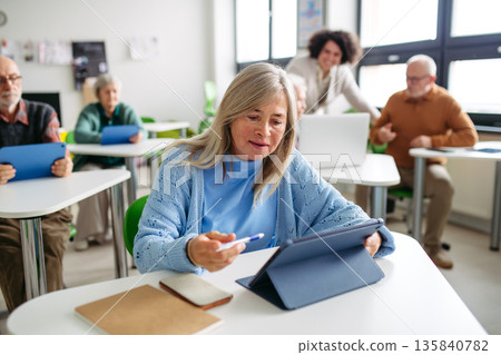 Older woman learning digital skills in community center. 135840782