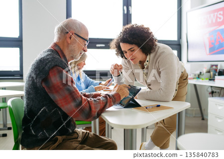 Senior man learning digital skills in community center. Senior man learning digital skills in community center. 135840783
