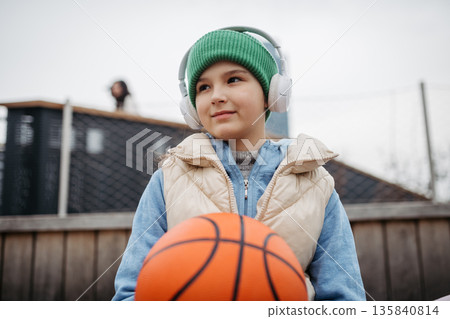 Young girl spending free time playing basketball in the city. 135840814