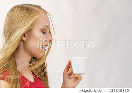 Blonde girl blowing hair holds coffee cup Blonde girl blowing hair holds coffee cup 135840880