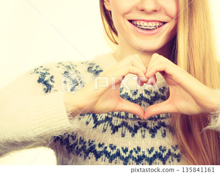 Teenage girl making heart sign with hands 135841161