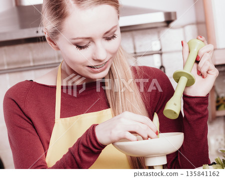 Woman in kitchen making vegetable smoothie juice 135841162