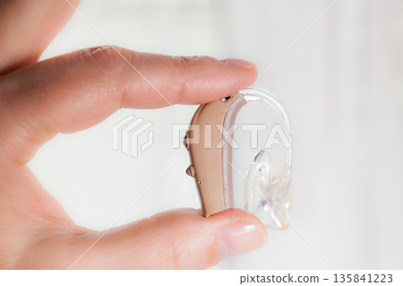 senior person holding hearing aid closeup senior person holding hearing aid closeup 135841223