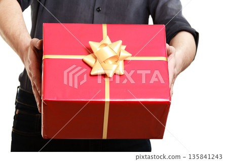 Holiday. Man giving red gift box with golden ribbon Holiday. Man giving red gift box with golden ribbon 135841243