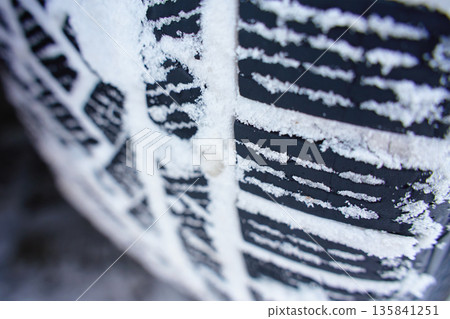 Winter tire tread pattern covered with snow close up Winter tire tread pattern covered with snow close up 135841251
